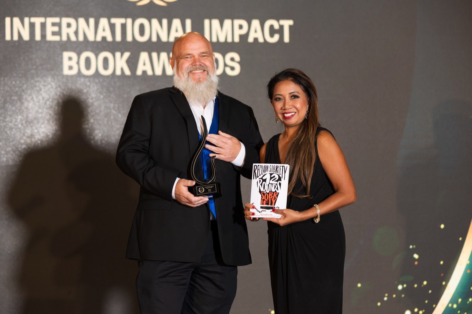 Ken Cox holding an award at the International Impact Book Awards
